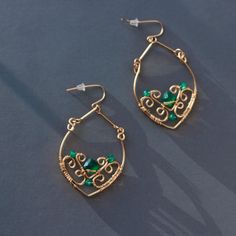 a pair of gold hoop earrings with green beads and filigrees on them