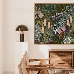 a painting hanging on the wall next to a wooden table and chairs in a room