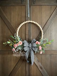 a wreath is hanging on the side of a barn door with flowers and pearls around it