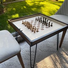 a chess board set up on top of a table with chairs in the back yard