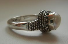 "Bali Suarti sterling silver and pearl ring. Small and beautiful, this ring has a soft iridescent white pearl, set in a raised bezel. The slightly domed pearl is encased in two rows of fine granulation pebbles and two rows of fine braiding. The sides have a striped-pebble vertical design. The back of the setting is solid and the band is thick. Beautifully made in the Balinese tradition and in excellent vintage condition. Please see detailed measurements below. > Size 5.5. *Thank you for doubl Silver Sterling Silver Pearl Ring, Handmade Silver Pearl Ring For Formal Occasions, Adjustable Silver Pearl Ring For Wedding, Silver Pearl Promise Ring Stamped 925, Adjustable Silver Pearl Promise Ring, Silver Pearl Open Ring Jewelry, Silver Open Ring With Pearl Drop, Handmade Vintage Pearl Ring In Sterling Silver, Silver Open Ring Pearl Ring