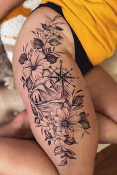 a woman's thigh with flowers and a compass tattoo on her left side leg