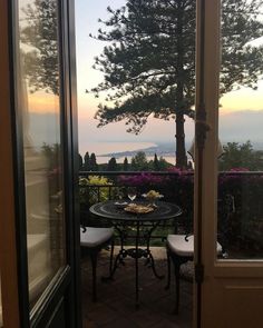 an outdoor table and chairs on a patio with the view out to sea in the distance