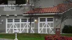 a house with two white garage doors and a red roof