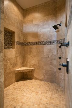 a walk in shower sitting next to a tiled wall and floor covered in brown tile