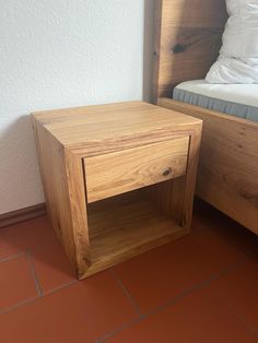 a small wooden table sitting on top of a red tile floor next to a bed