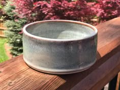 a gray bowl sitting on top of a wooden rail