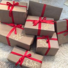 six wrapped presents with red ribbon on them sitting on a white carpeted floor next to each other