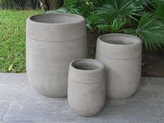 three cement planters sitting on top of a stone slab in front of a palm tree