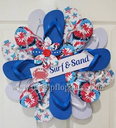 a wreath made out of flip flops is hanging on the front door with a sign that says surf & sand