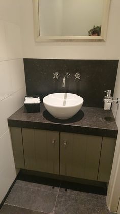 a bathroom sink sitting on top of a counter next to a mirror and toilet paper