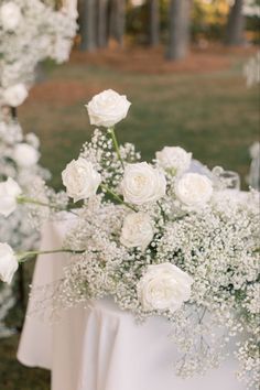 white flowers and baby's breath are on the table at this outdoor wedding ceremony