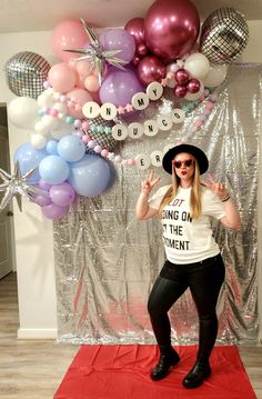 a woman standing on a red carpet in front of balloons and signs that say no one is