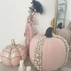 some pink pumpkins with pearls on them and a black bird figurine next to it