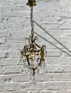 a chandelier hanging from the ceiling in front of a white brick wall