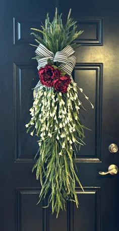 a door decorated with flowers and greenery hanging from the side of a black door