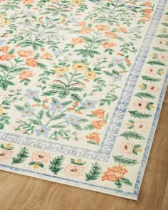 an area rug with flowers and leaves on the floor in front of a wooden floor