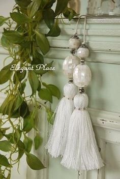 white tasselled ornaments hanging on a wall next to a potted green plant