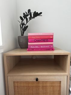 three books are stacked on top of each other in front of a small wooden cabinet