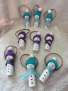 snowmen made out of marshmallows on a white blanket with blue and purple knitted hats