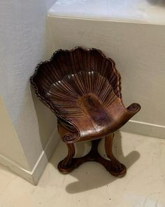 a wooden chair sitting next to a white wall in a room with tile flooring