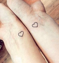 two people with matching tattoos on their arms, one holding the other's hand