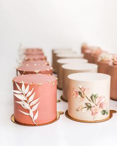 there are many different colored cups on the table with gold trimmings and flowers painted on them