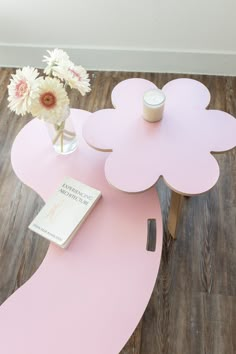 a pink table with flowers and a book on it