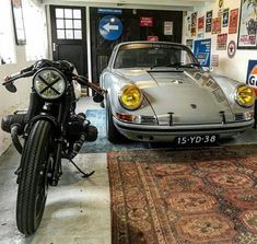 a motorcycle parked next to a car in a room with posters on the wall behind it