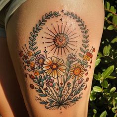 a woman's thigh with flowers and stars on the side, in front of bushes