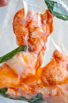 some food wrapped in plastic sitting on top of a white plate with green leafy leaves