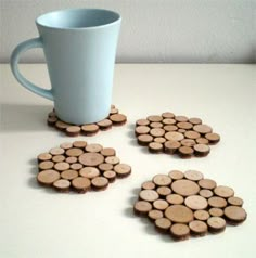 four pieces of wood are arranged in the shape of circles next to a cup on a table