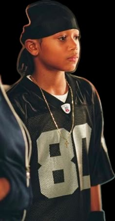 a young boy wearing a football jersey and hat