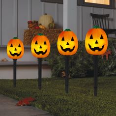 three lighted pumpkins in the shape of jack - o'- lanternes on lawn