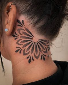 a woman's neck with a black and white tattoo design on her left side