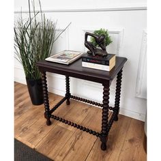 a wooden table with two books on it and a plant in the corner next to it