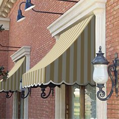 an awning on the side of a brick building with two lamps hanging from it's sides