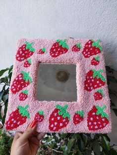 someone is holding up a pink frame with strawberries on it