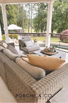 an outdoor living room with wicker furniture and large windows overlooking the backyard pool area