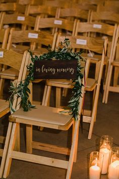 a row of wooden chairs with candles in front of them and a sign that says in loving memory