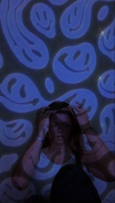 a woman with her hands on her head in front of a blue and white wall