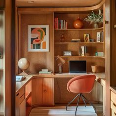 a home office with an orange chair in the corner and bookshelves on the wall