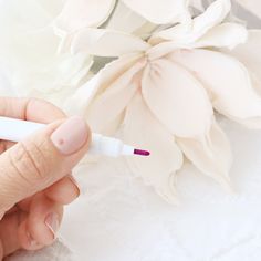 a person holding a pen in their left hand near a white flower with pink tips