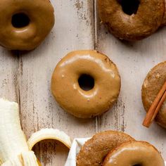 doughnuts and bananas on a wooden surface with cinnamon sticks sticking out of them