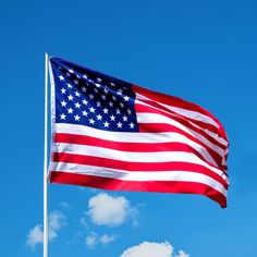 an american flag is flying in the wind on a clear day with blue sky and white clouds