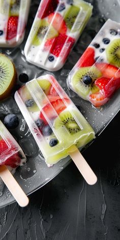 fruit popsicles with kiwi, blueberries and strawberries in them on a plate