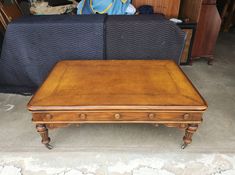 a wooden table sitting on top of a floor next to a couch