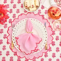 the table is set with pink napkins, plates and utensils on it