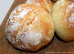 three loaves of bread sitting on top of a wooden cutting board