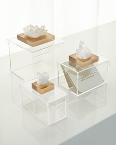 three clear acrylic boxes with different types of crystals in them on a white surface